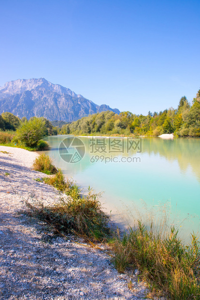 古老的海岸景观清蓝的水鲜花小石头沙滩和山丘图片