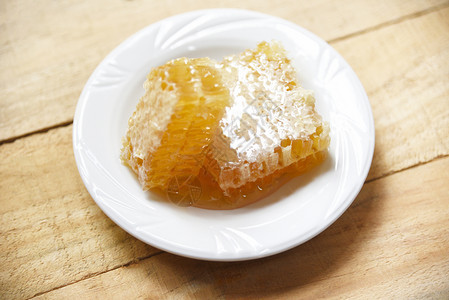 白色盘子上黄甜蜂窝切片天然健康食品背景图片