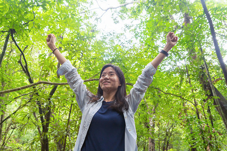 快乐的亚洲妇女在泰国坎沙纳布里家公园旅行和户外度假时在热带森林中放松和享受树木图片