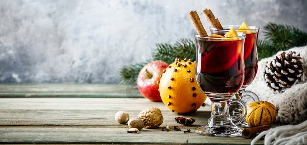 木制桌上配有香料和橙片的混合葡萄酒图片