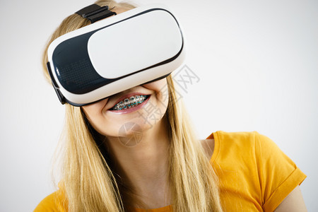 年轻女穿着虚拟真实的护目镜头盔Vrbox工作室拍摄灰色女孩穿着虚拟真实的护目镜图片