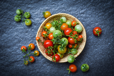 含绿色和收获的新鲜番茄有机红在黑暗背景的篮子中收成熟红番茄图片