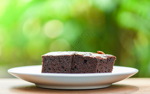 餐桌上的蛋糕巧克力切片木制和自然绿色背景上的坚果图片