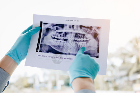 亚洲男牙医正在分析病人X光照片图片