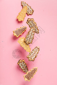 圣诞姜饼干以圣诞树为形状依粉红面背景坠落或飞动圣诞姜饼干树为果掉落或飞动的形状图片