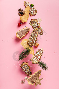 圣诞姜饼干以圣诞树为形状依粉红面背景坠落或飞动圣诞姜饼干树为果掉落或飞动的形状图片