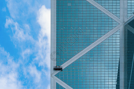 由一群人工或洗衣组成的公司在高楼办大上打扫玻璃在香港市中心外的一座高楼上安装有线电中午时在城市的蓝天空下打扫窗户图片