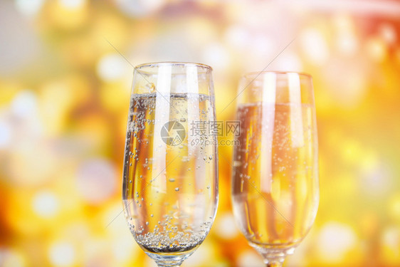 与香槟杯一起庆祝冬季节日盛装的圣诞光灯布满了金色背景图片