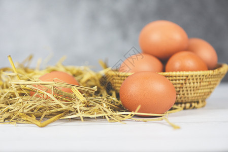 篮子和稻草上新鲜鸡蛋配有木制桌底背景最顶端视图从农产品中收集的生鸡蛋图片