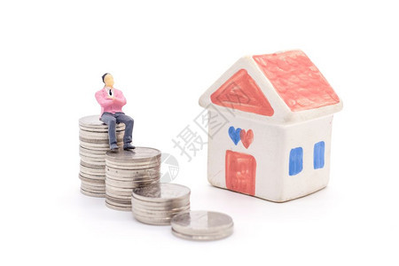 微型商人站在硬币和后面的房屋上储蓄和贷款概念图片