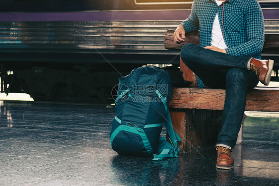 背包男坐在板凳上等火车站图片