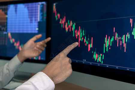 商业贩小组在办公室计算机屏幕上指出图表和分析股票市场图片
