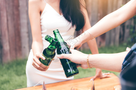 紧关上年轻的亚洲人拿着啤酒瓶和喝在一起图片
