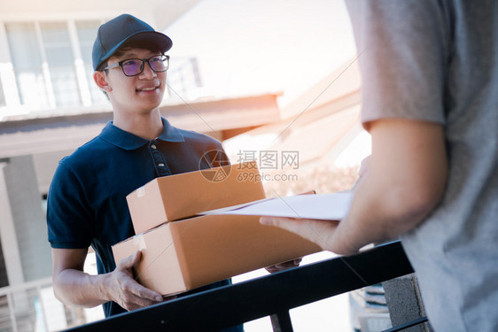 亚洲货运承人持有一个纸箱里面装着货包接收方正在签署货包图片
