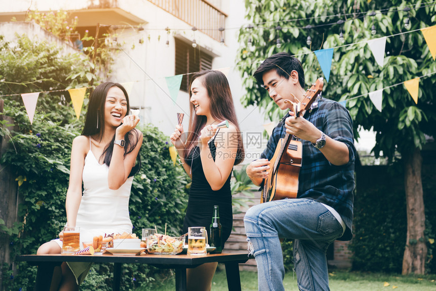 女人喜欢喝酒派对男人弹吉他在家里花园户外唱歌图片