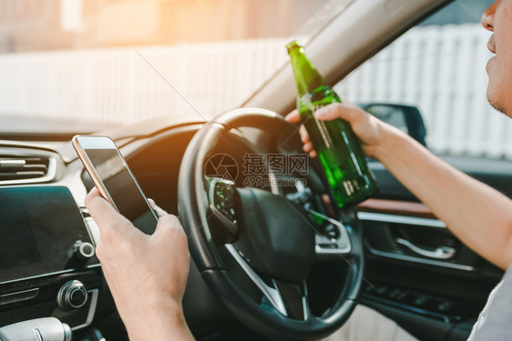 男子在车里喝酒并使用手机图片