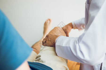 理疗师正在用病人膝盖的手柄检查疼痛情况图片