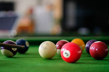 Man手和Cue臂在玩Snooker游戏或准备在绿色球桌上绿色盘上有多彩的Snooker球图片