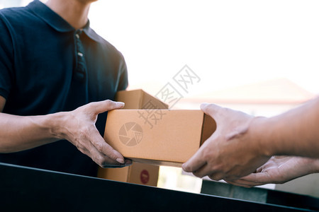 亚洲货运承人持有一个纸箱里面装着货包接收方正在签署货包图片