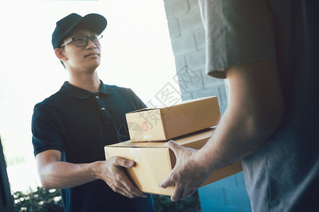 亚洲货运承人持有一个纸箱里面装着货包接收方正在签署货包图片