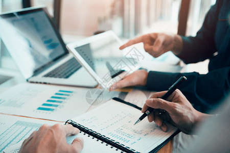 商业伙伴共同工作人员编写成本工作进度报告使用平板片分析公司财务预算报告图表和在办公室规划未来图片