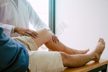 理疗师正在用病人膝盖的手柄检查疼痛情况图片