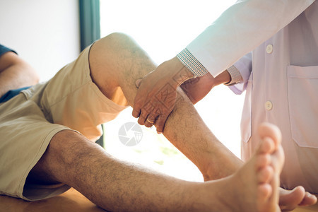 理疗师用手按病人小腿检查诊所疼痛和按摩情况图片
