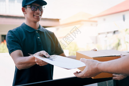 年轻的亚洲男子在向持有签名文件的妇女送纸箱时微笑图片
