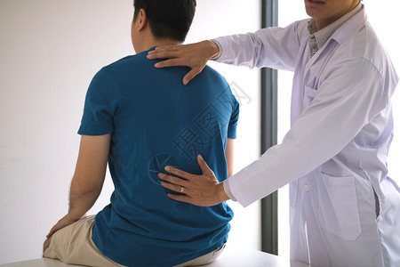 理疗师用手检查病人的背部图片