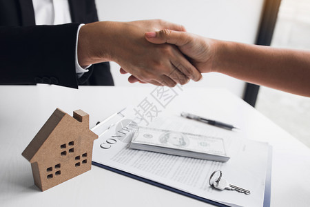 家庭销售代理商和买家努力签署新房和握手图片