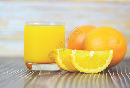 玻璃中的橙汁和木制新鲜橙子水果片图片