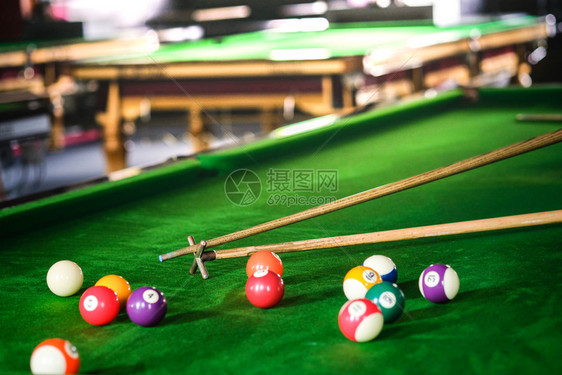 Man手和Cue臂在玩Snooker游戏或准备在绿色球桌上绿色盘上有多彩的Snooker球图片