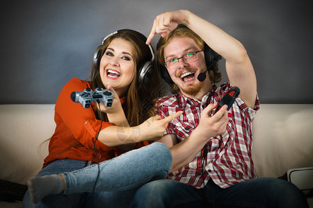 快乐的情侣通过一起玩电子游戏享受休闲时间图片