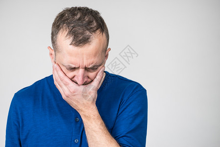 忧郁悲伤焦虑的成年男子蒙住嘴感到内疚和羞愧图片