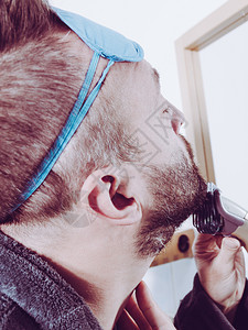 胡子人用电动刮刀子用镜中长的胡子涂着困睡眼罩的照顾面部头发人剃胡子修剪他胡子图片