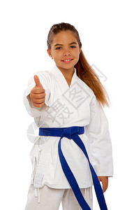 穿着白色和服的空手道女孩和蓝腰带显示一个完全举起拇指的标志图片