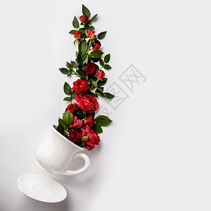 由咖啡或茶杯以及白底红玫瑰制作的创意布局图片