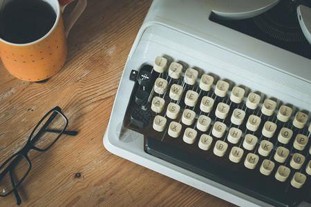 旧式打字机眼镜和木制桌上咖啡杯图片