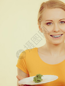 快乐的年轻女子即将吃着盘和微笑的生菜满图像颜色的微笑着女子拿盘和生菜图片