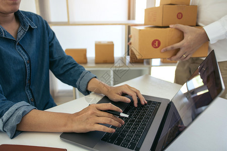两个企业主正在共同努力包装产品检查客户和在家的笔记本电脑上订购单图片