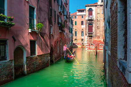 Gondolier在意大利威尼斯阳光明媚的威尼斯运河上用照片般的威尼斯运河送游客到传统的贡多拉图片
