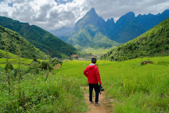 一名亚洲旅游男子在越南萨帕Sapa的旅游行和假期概念中夏季在Fansipan山上与稻田谷一起观望图片