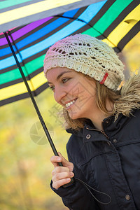 穿蓝大衣和雨伞的年轻女孩正在秋季森林散步图片