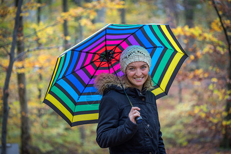穿蓝大衣和雨伞的年轻女孩正在秋季森林散步图片