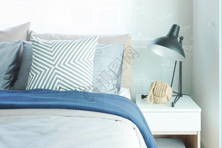 现代经典风格的室内式卧床头桌上有枕和黑色阅读灯图片