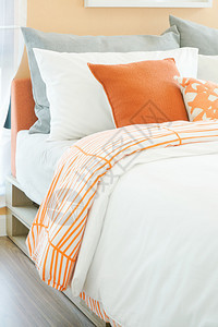 室内现代卧床上有橙色白和灰枕头卷图片