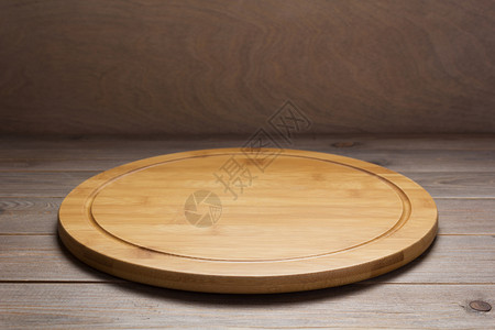 在前木板背景的生锈制桌子上切比萨饼板图片
