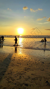 在印度尼西亚巴厘的库塔海滩享受戏剧日落的人们轮椅图片