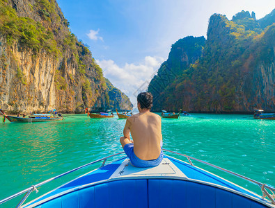 一名亚洲男子旅游者在暑假行期间在普吉岛Krabi夏季乘游假旅行蓝色绿的海水坐船在Krabi上潜或水图片