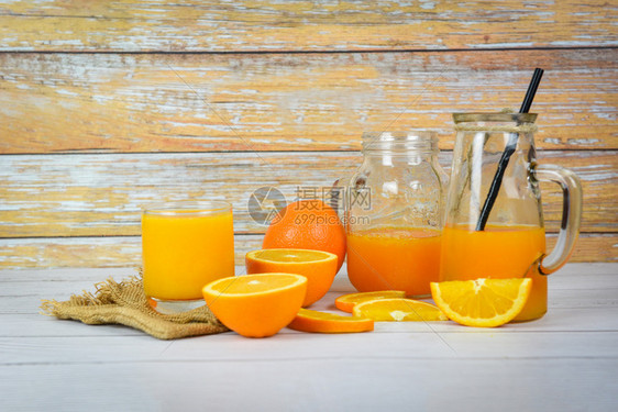 玻璃罐中的橙子汁和木制桌上新鲜橙子水果片木本底的死玻璃汁图片